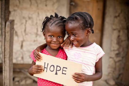 Zwei Kinder halten gemeinsam ein Schild mit der Aufschrift HOPE